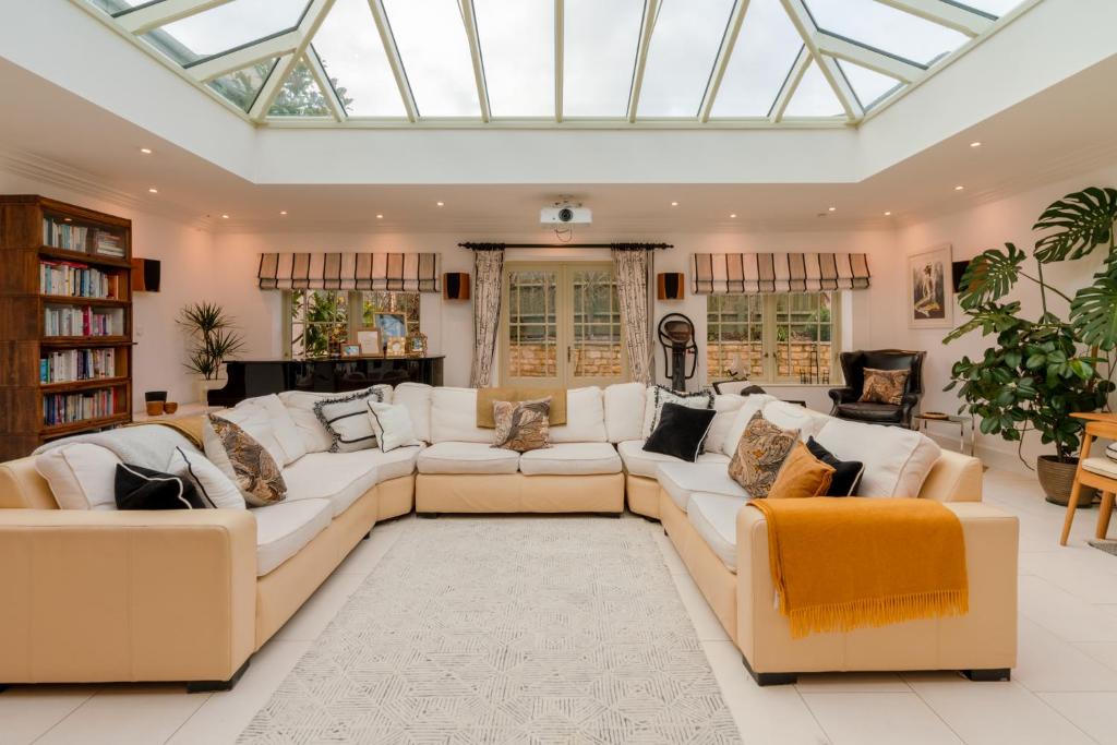 a conservatory living room with white furniture and a skylight at Milestone in Winchcombe