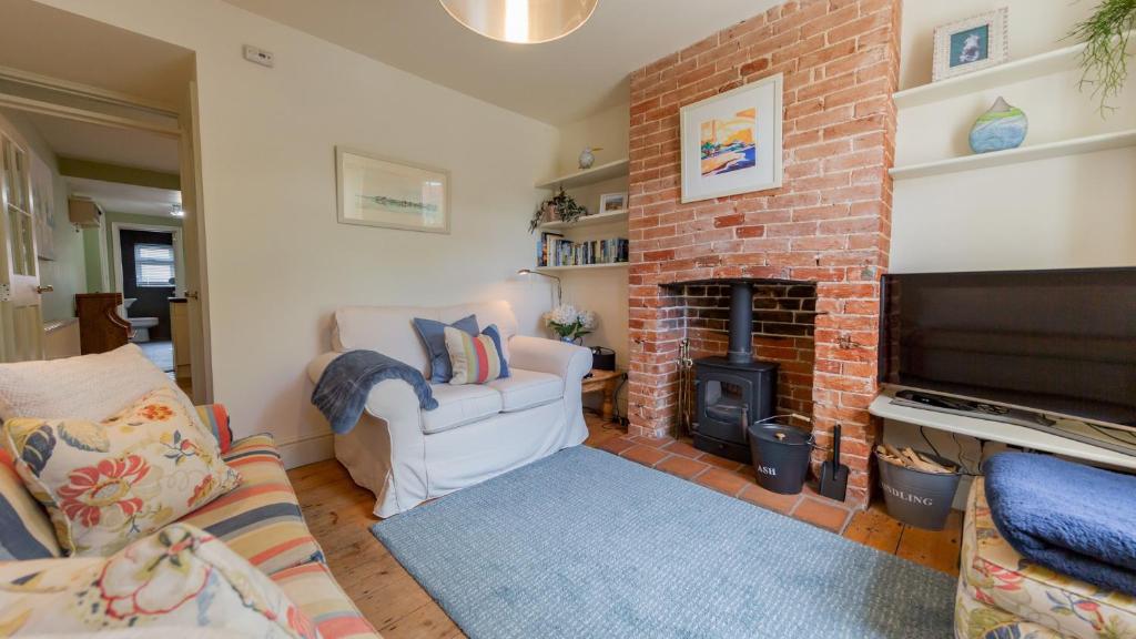 ein Wohnzimmer mit einem gemauerten Kamin und einem TV in der Unterkunft Palmer's Cottage in Southwold