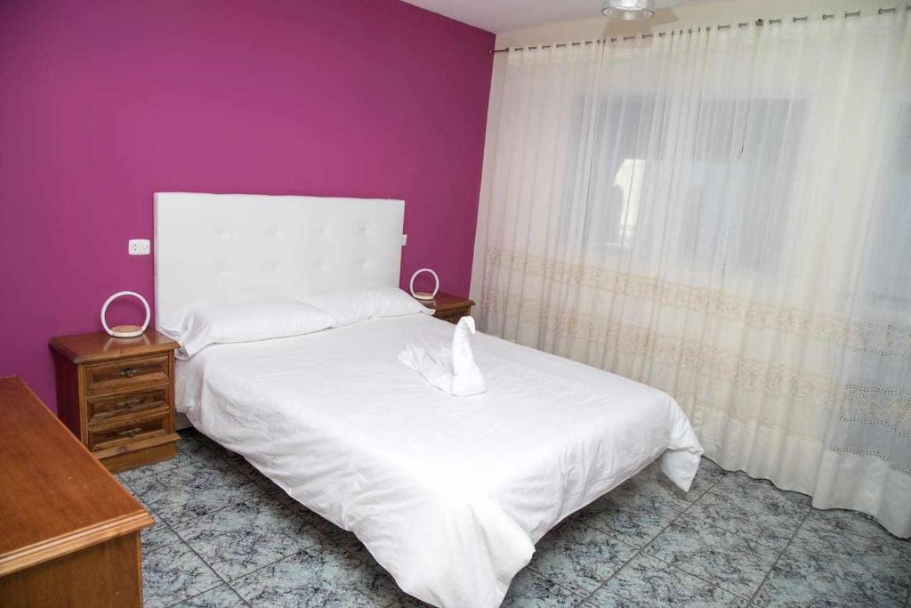 1 dormitorio con cama blanca y pared morada en El Olivar Agloipe Ahigal TRCC, en Ahigal