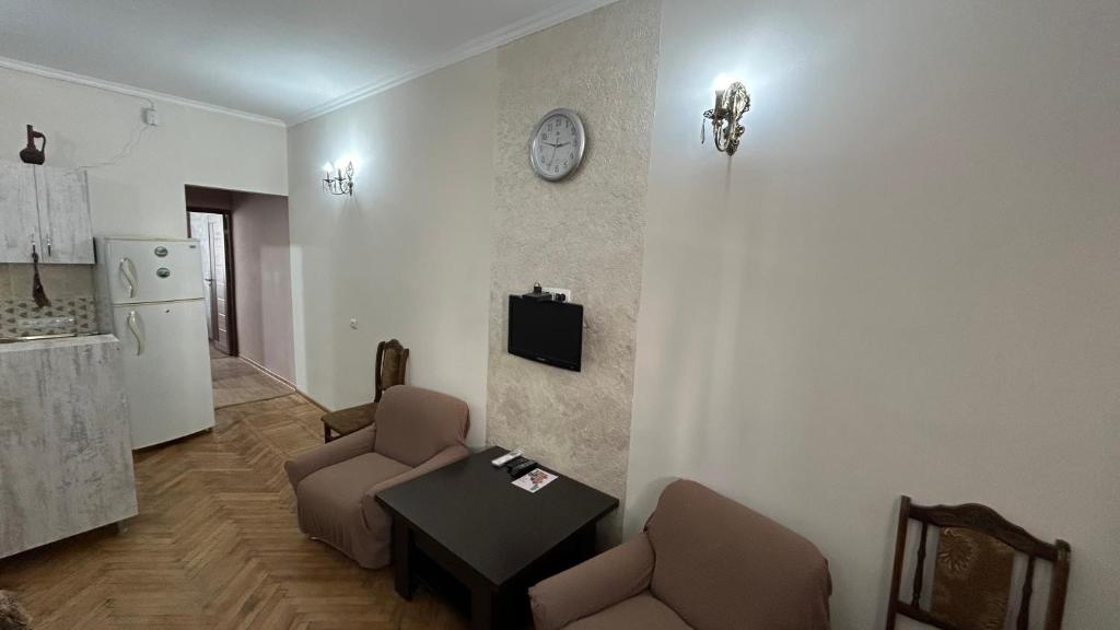 ein Wohnzimmer mit 2 Stühlen, einem Tisch und einer Uhr in der Unterkunft DS Appartment in Yerevan in Yerevan