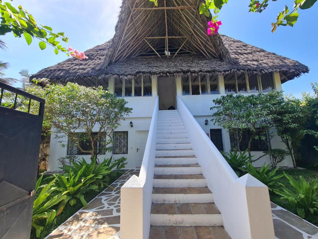 a staircase leading up to a house with a thatched roof at Villa Yasmin in Watamu