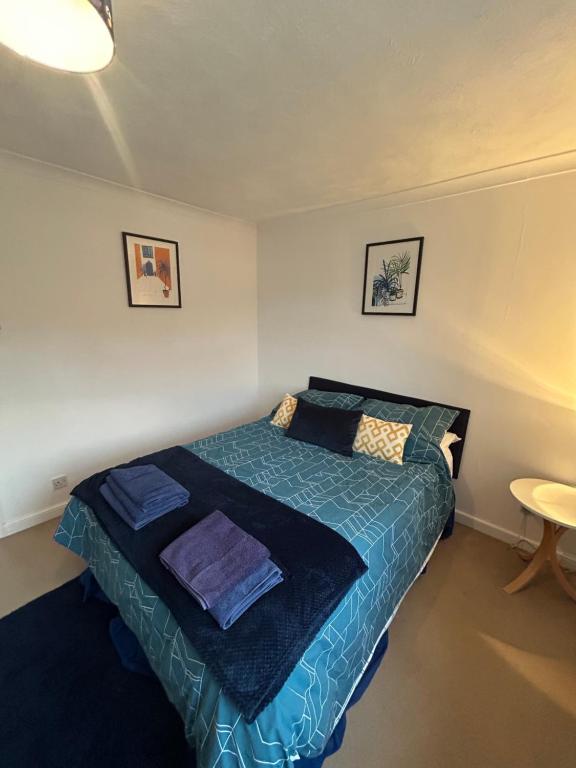 a bedroom with a bed with a blue comforter at KB51 Charming 2 bed house in Horsham, pets very welcome and long stays with easy access to London, Brighton and Gatwick in Warnham