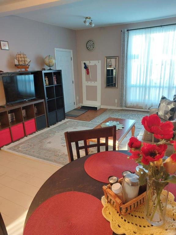 una sala de estar con una mesa con flores. en Appartement Cartier 2, en Longueuil