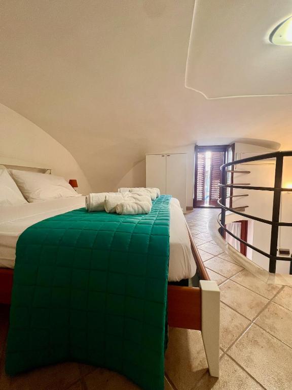 a bedroom with a bed with a green blanket at Il Balconcino in Gaeta