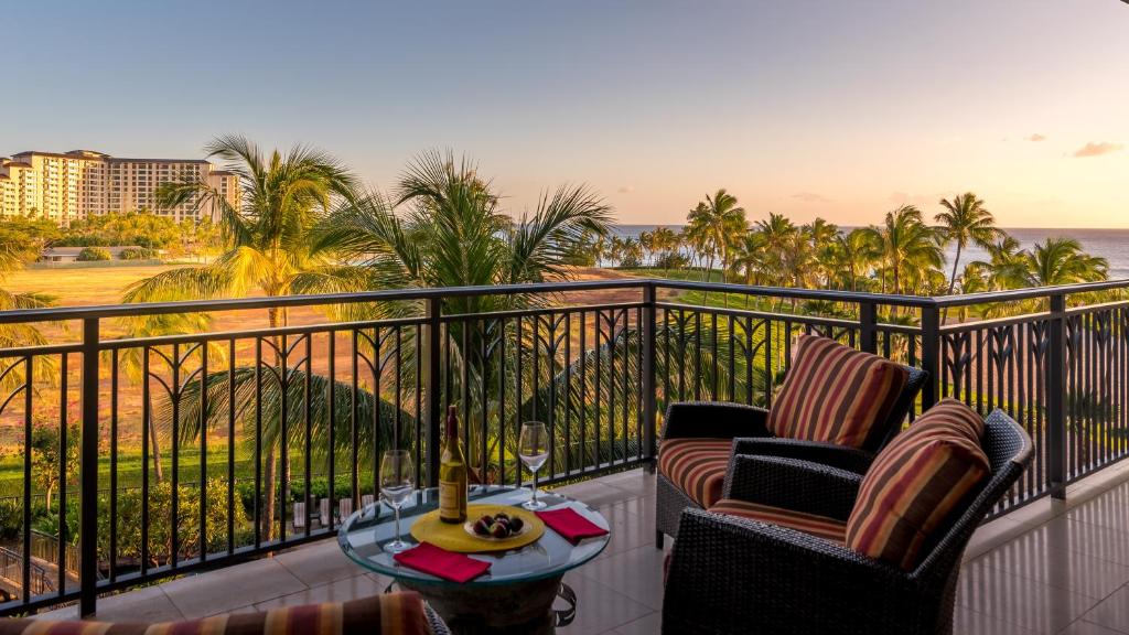 a balcony with two chairs and a table with a wine glass at Ko Olina Beach Villas B505 in Kapolei