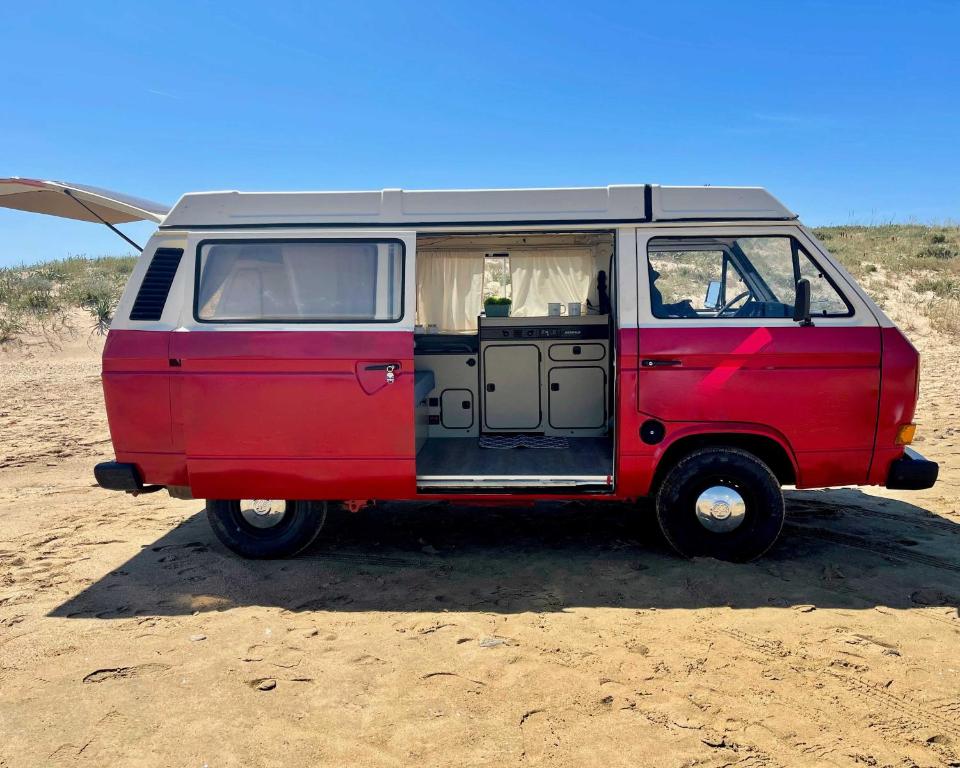 a red and gray van parked in the desert at The Feather Van in Puerto del Rosario