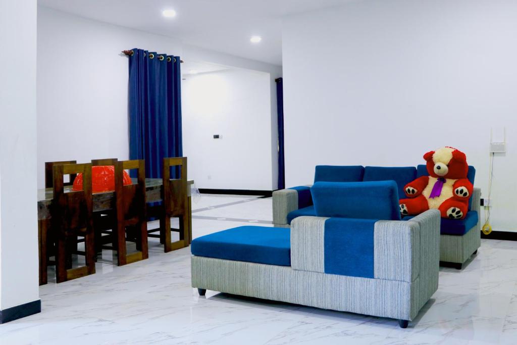 Una sala de estar con un sofá azul con un animal de peluche. en Nirwana Villa, en Mirissa
