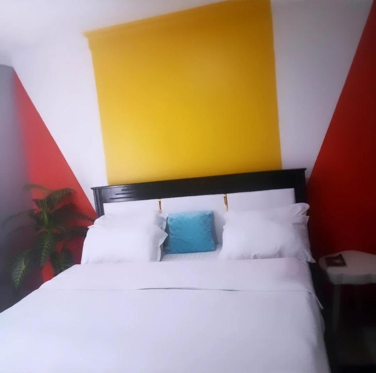 um quarto com uma cama branca e uma parede amarela e vermelha em Beniez apartment em Kampala