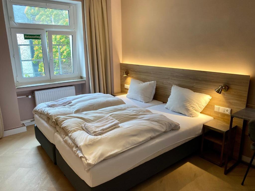 a bedroom with a large bed with a wooden headboard at Hotel Petite Königsallee SELF CHECK-IN in Düsseldorf