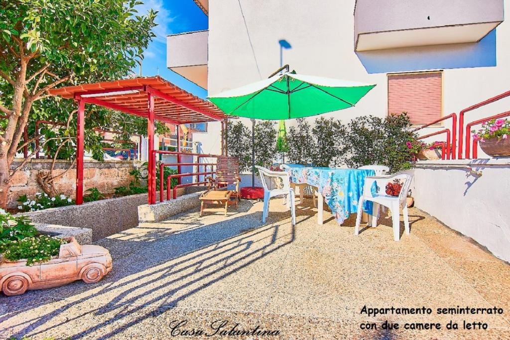 eine Terrasse mit einem Tisch und einem Sonnenschirm in der Unterkunft CasaSalentina in Santa Maria al Bagno