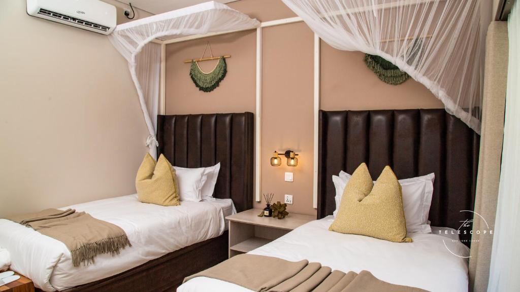 two beds in a room with white and yellow pillows at The Telescope Boutique Lodge in Victoria Falls