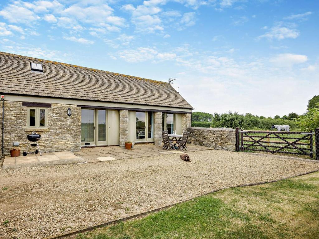 a stone house with a patio and a fence at 1 Bed in Cirencester 57684 in Kemble