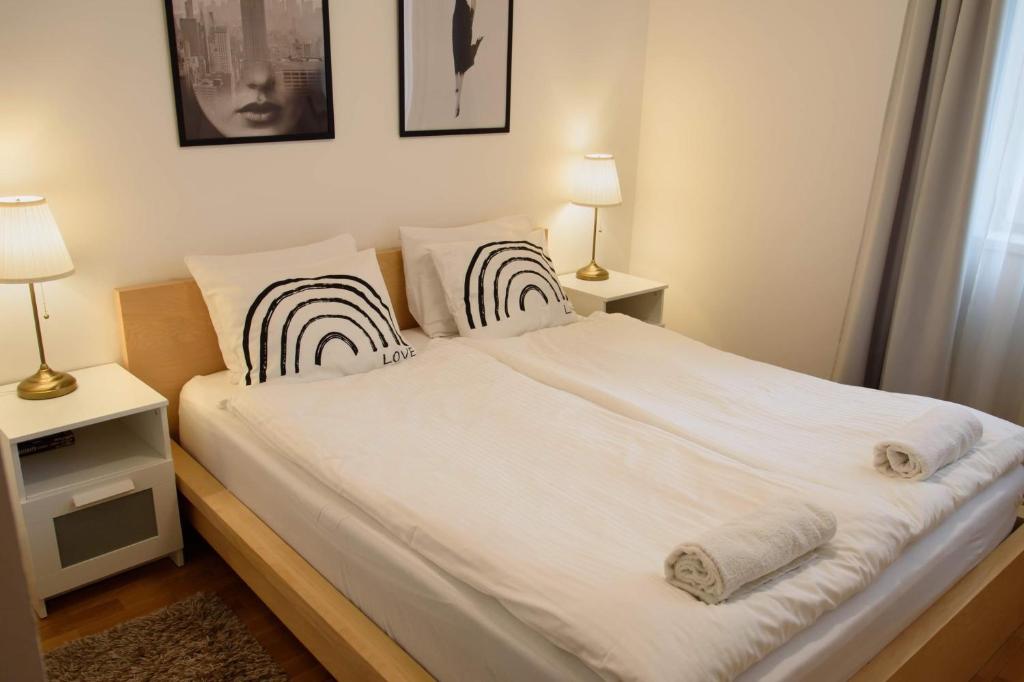 een slaapkamer met een bed met witte lakens en 2 lampen bij Peony Káldy Apartman Free Garage under the house in Boedapest