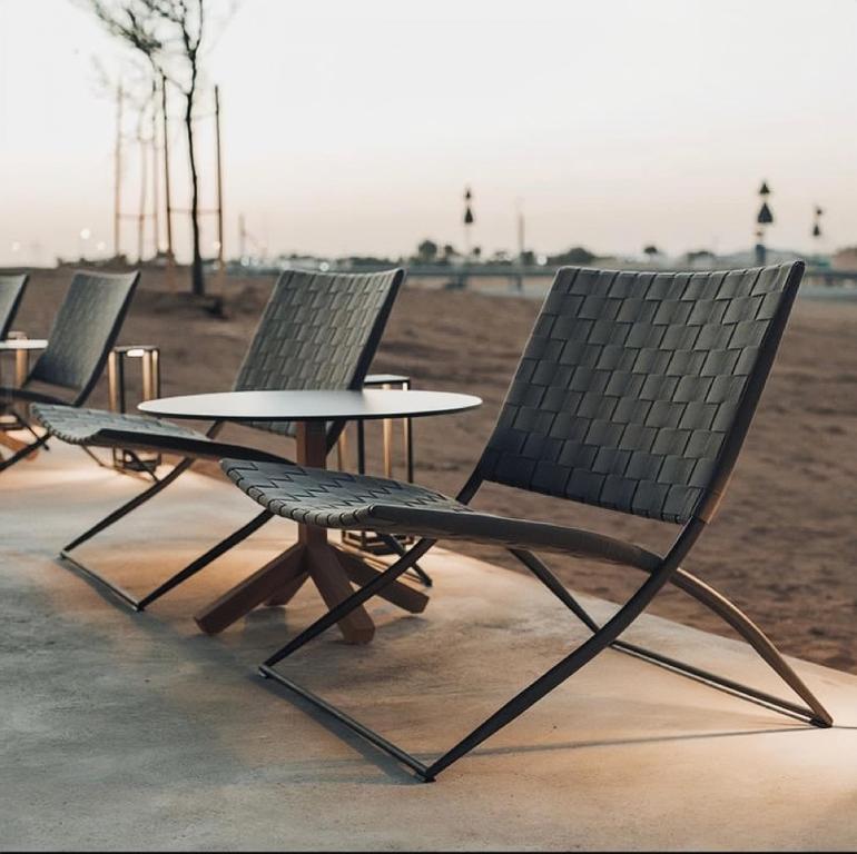 een groep stoelen en een tafel en een veld bij Alora Wadi Rum Luxury in Wadi Rum