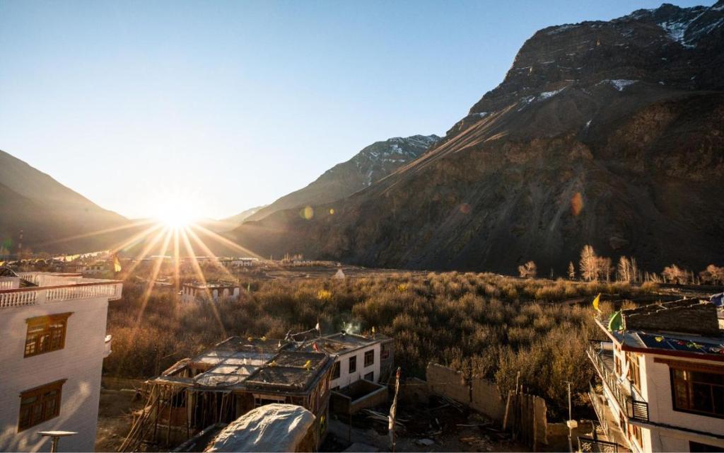 a view of a city with the sun shining through a mountain at Green Tara Homestay by StayApart in Tabo
