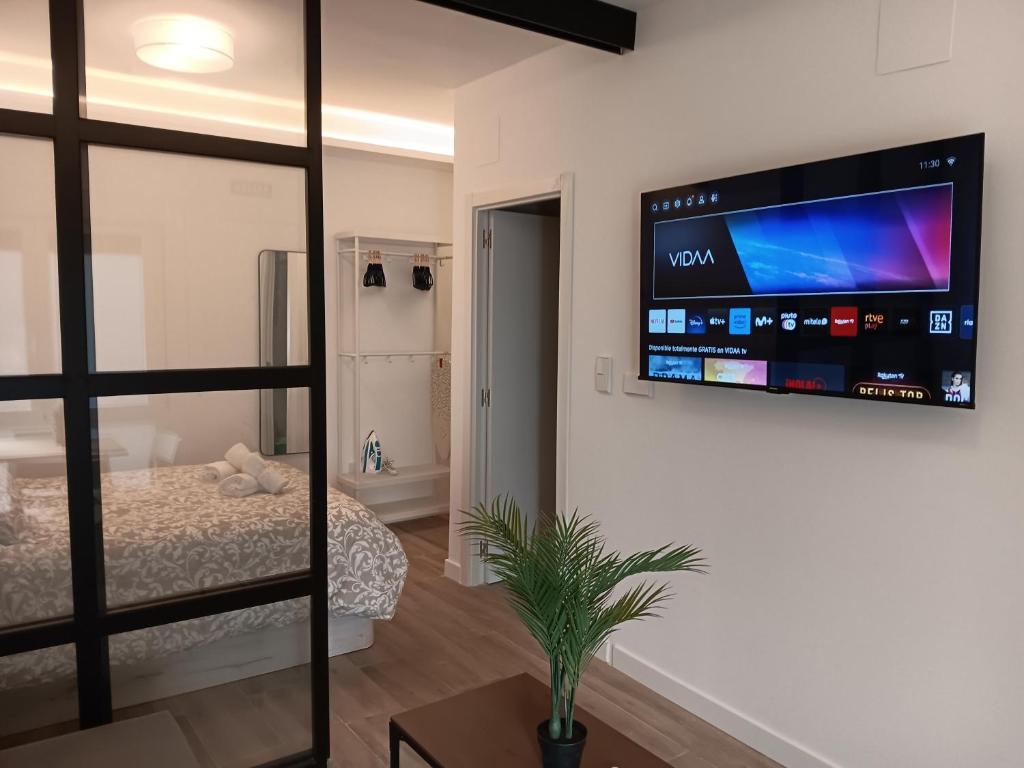 a bedroom with a bed and a flat screen tv on the wall at Puerta de Hierro Apartments in Madrid