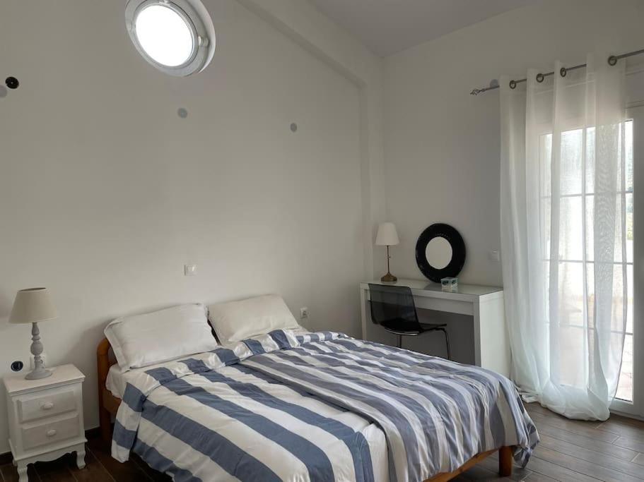 a white bedroom with a bed and a window at Villa Vlamari in Vathý