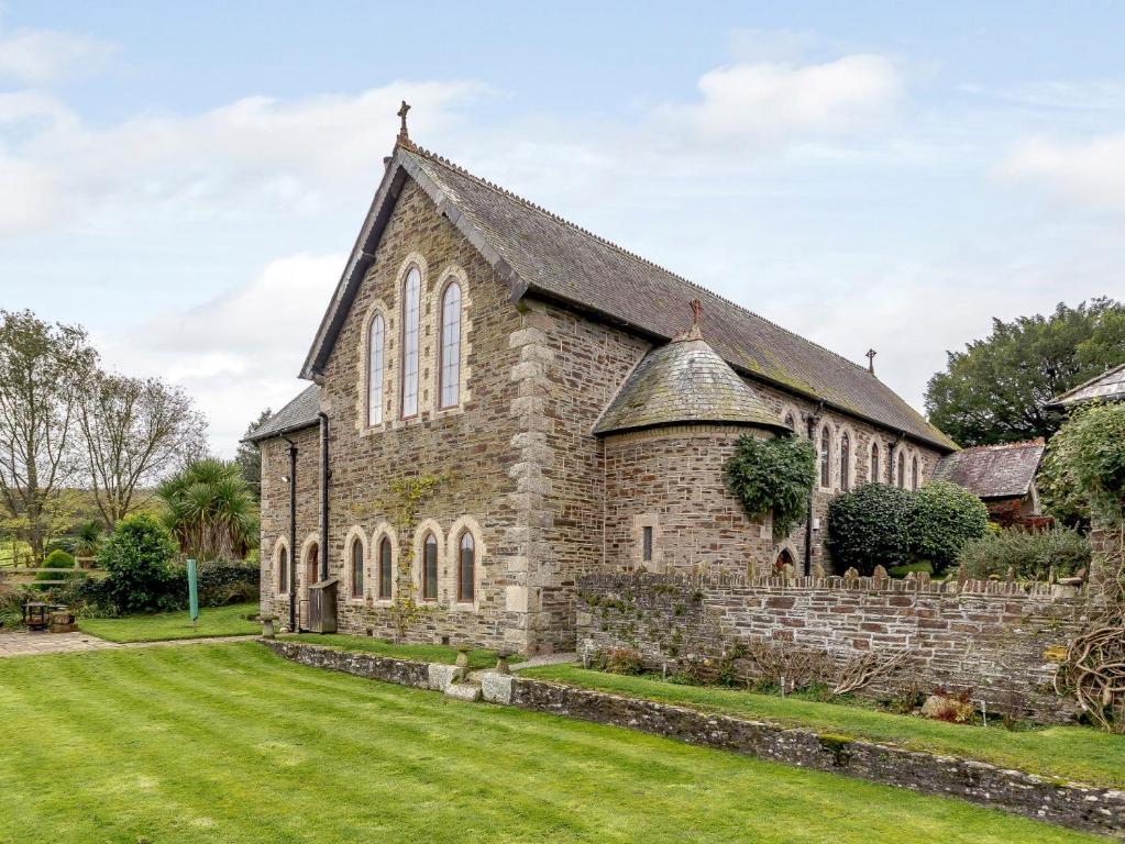 eine alte Steinkirche mit einem Rasenplatz in der Unterkunft 4 Bed in Latchley 77480 in Sydenham Damerel