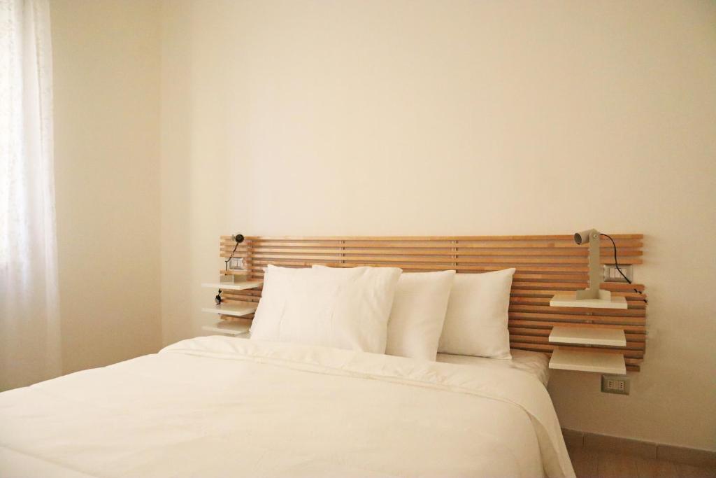 a bedroom with a white bed with a wooden headboard at Corsico Comfort Home in Corsico