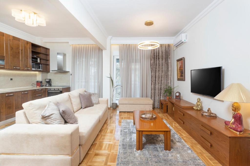 a living room with a white couch and a tv at King George 32 Luxury Apartment in Thessaloniki