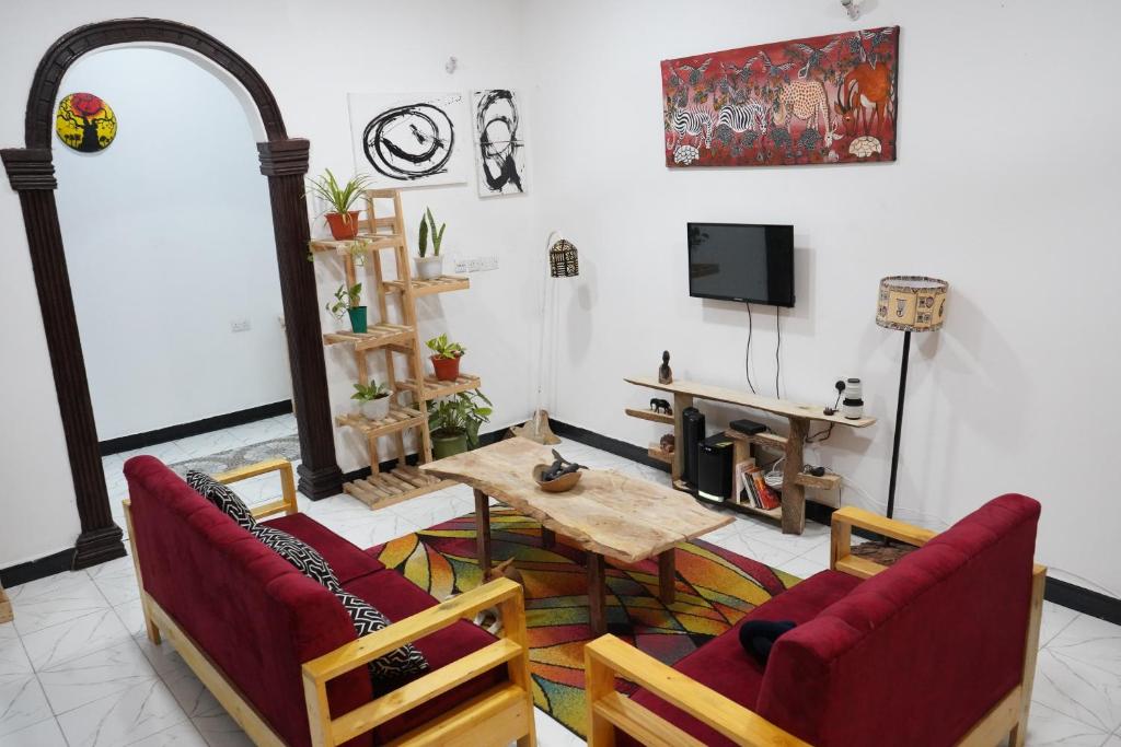 達累斯薩拉姆的住宿－2 Bedroom spacious Cozy Home in Kigamboni,10 min Walk to Beach，客厅配有桌椅和电视。