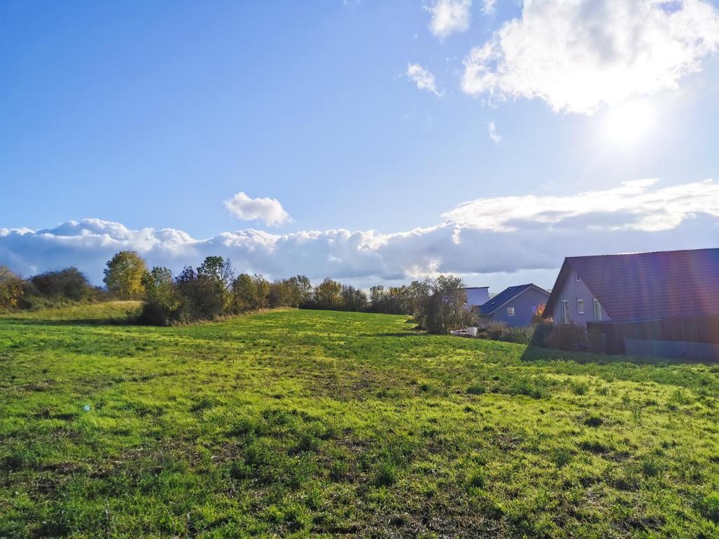 a field with a barn and the sun in the sky at Ferienwohnung Löwenstern Niederstetten in Niederstetten