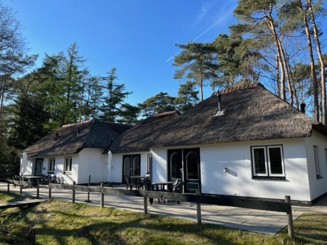 オッテルローにあるFamiliehuis De Sparの茅葺き屋根の白い建物2棟