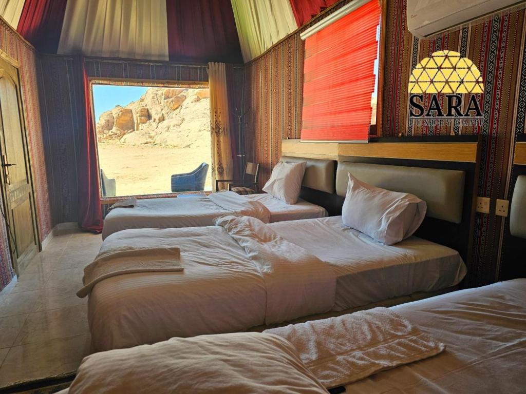 a hotel room with three beds with a view of the desert at SARA LUXURY RUM CAMp in Wadi Rum