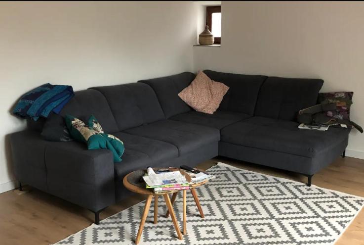 ein schwarzes Sofa im Wohnzimmer mit einem Tisch in der Unterkunft Galeriehaus in Münnerstadt