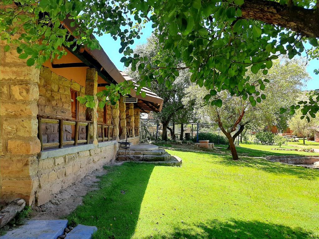 a stone building with a grass yard next to a tree at Eingedi Retreat in Kommissiepoort