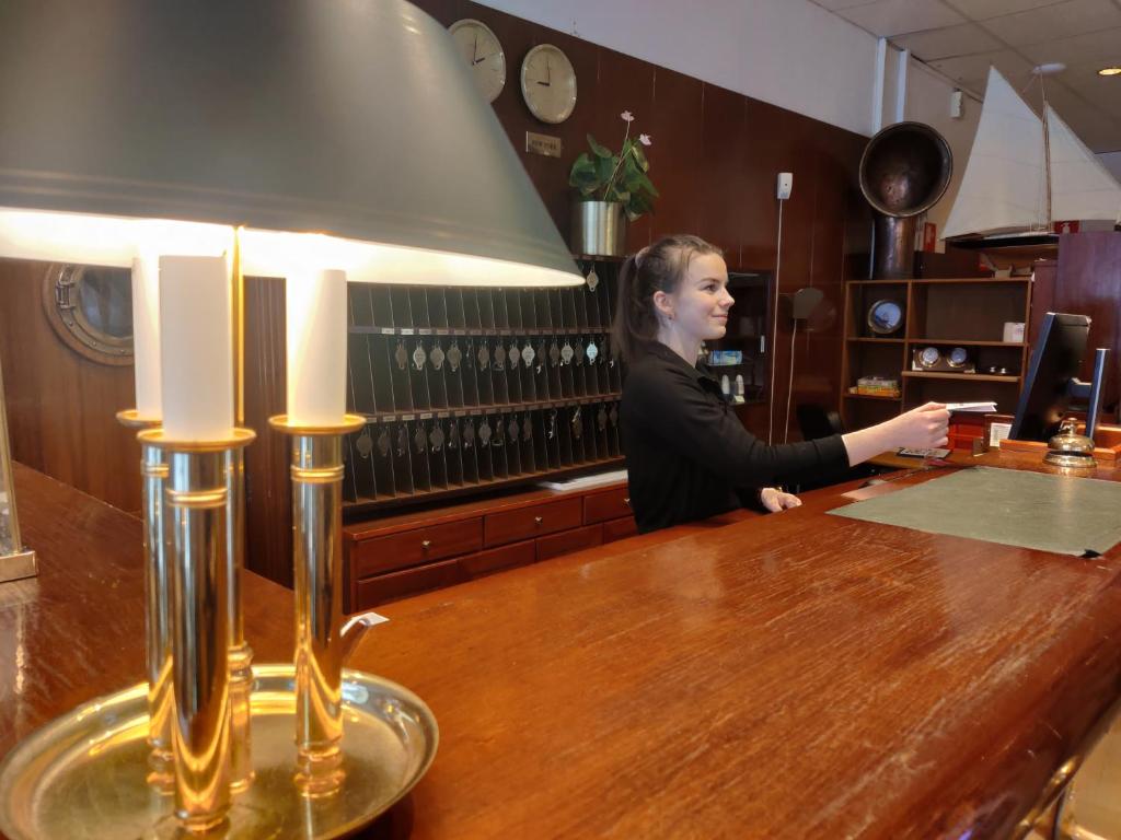 a woman standing at a counter in a bar at Hotell City in Motala