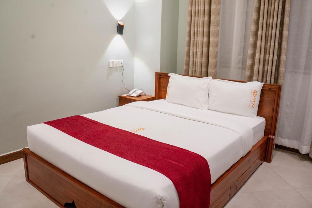 a bedroom with a large bed with a red blanket at Nexa Hotel in Arusha