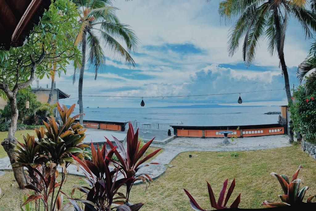 a view of the ocean from a resort with palm trees at Bungalow Geringsing in Candidasa