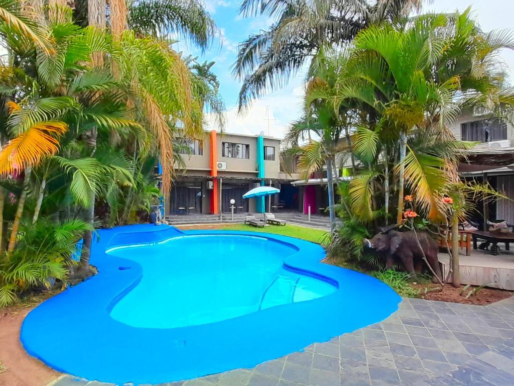 a pool in front of a resort with palm trees at Elephant Springs in Bela-Bela