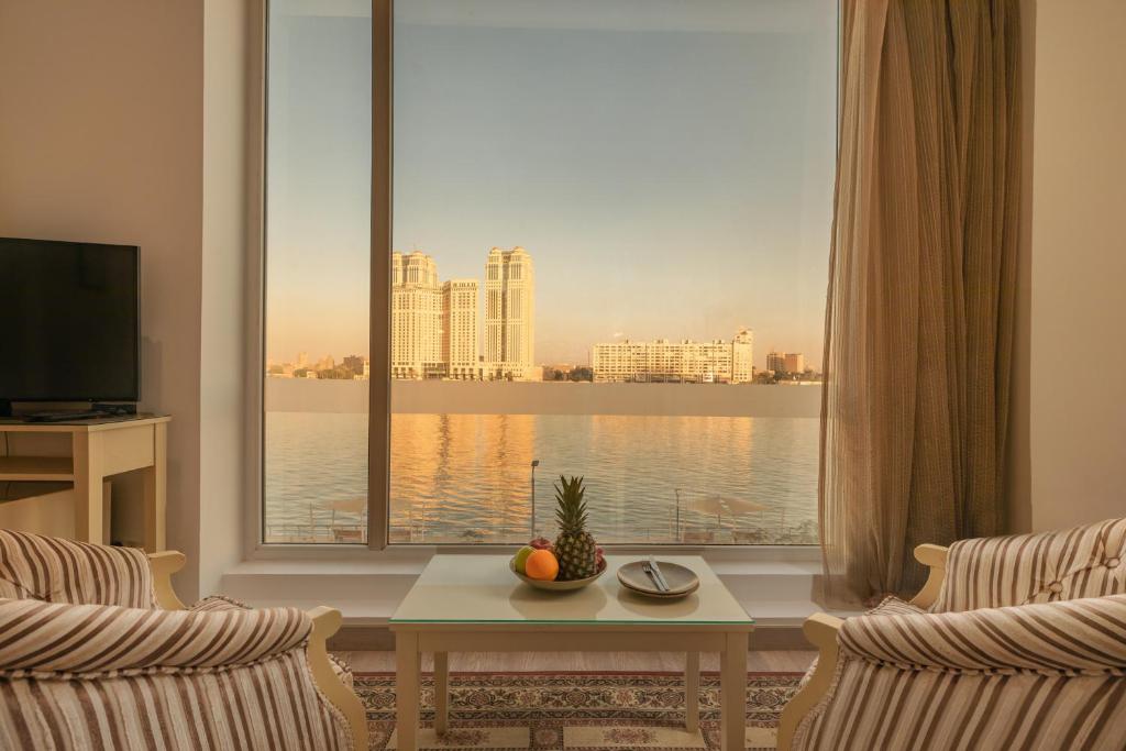 ein Wohnzimmer mit einem großen Fenster mit Blick auf das Wasser in der Unterkunft Riverside Hotel in Kairo