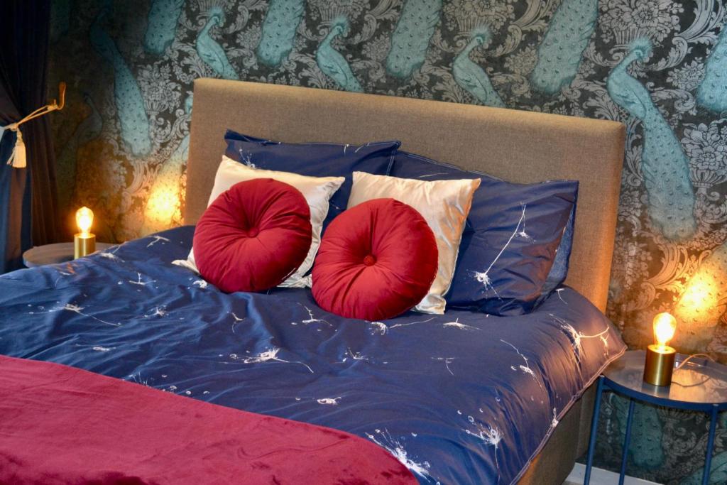 two red pillows sitting on a bed with blue sheets at The Flowerhouse in Zandvoort