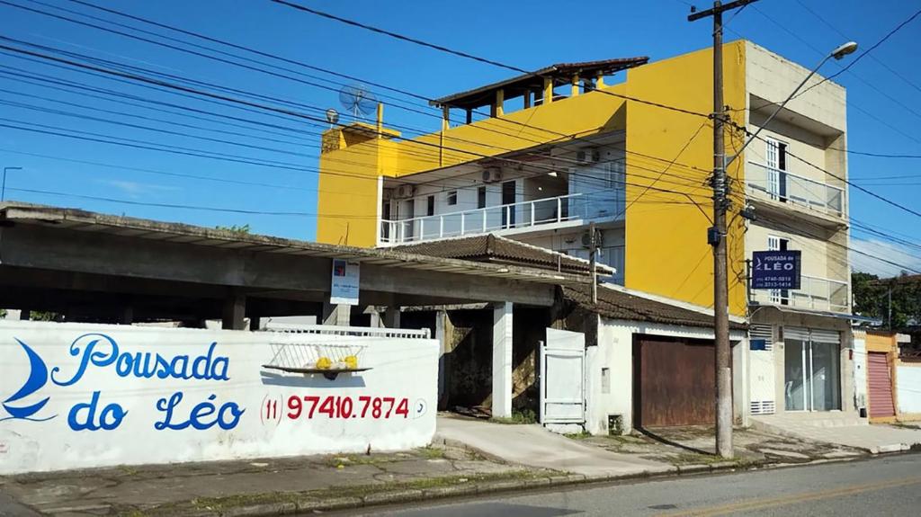 un edificio amarillo al lado de una calle en Pousada Do Léo, en Bertioga