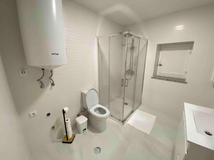 uma casa de banho branca com um chuveiro e um WC. em Casa Bossa Nova no Fundão