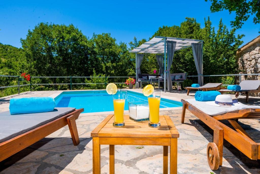 a pool with two tables with drinks on them at Villa Ognjistar in the hinterland of Makarska Riviera in Zmijavci