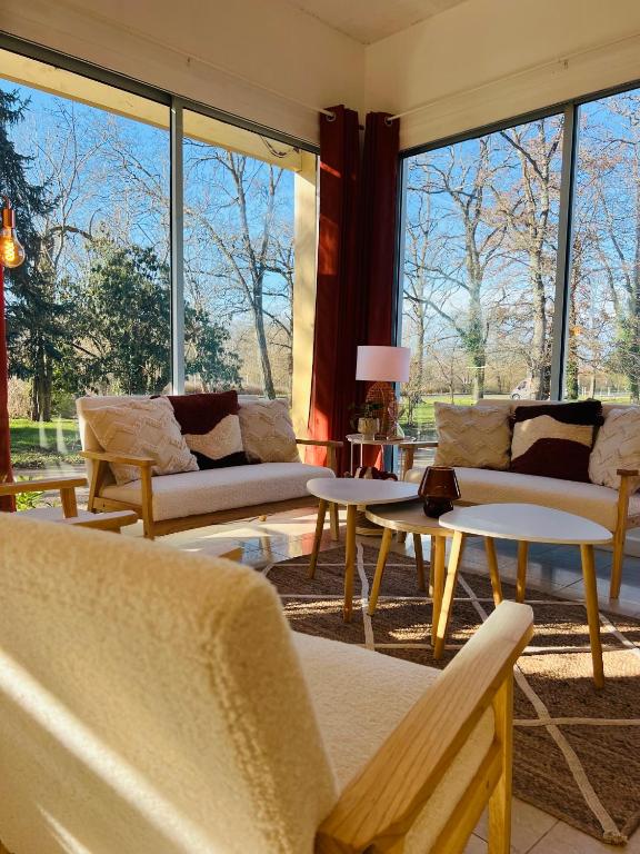 - un salon avec des canapés, des tables et de grandes fenêtres dans l'établissement Motel Les Broussailles, à Mesves-sur-Loire