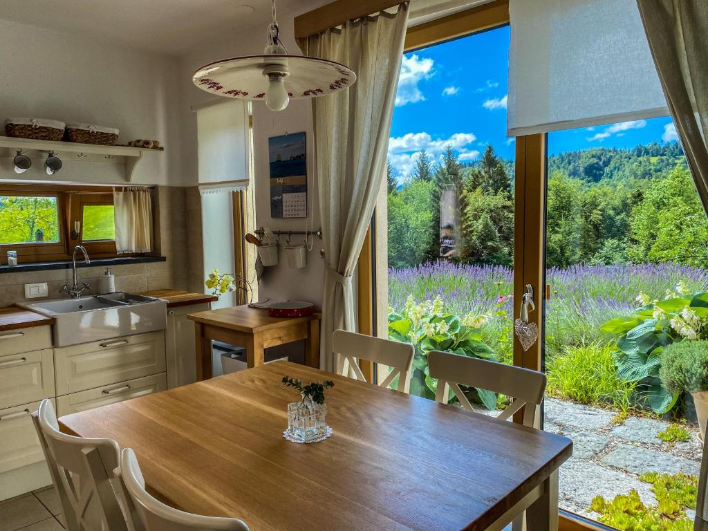 a kitchen with a wooden table and a large window at Na Kupčku Estate "Nature Reatreat & Wellness" in Idrija