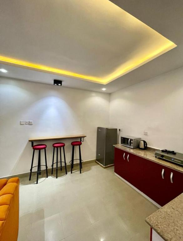 a kitchen with two bar stools and a refrigerator at AL_MUBARAK ,APARTMENT in Ikeja