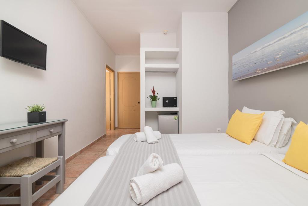 a white room with two beds and a tv at Cavo Doro in Kalamaki
