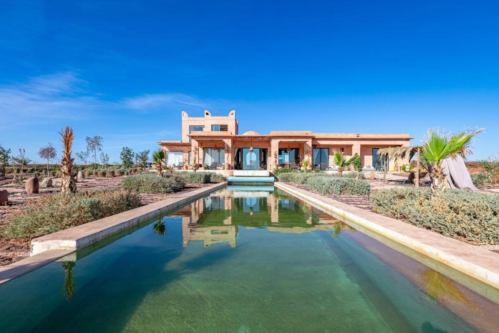 a home with a pool in front of a house at La villa Kela Serene 4 suites in Marrakech