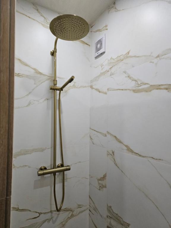 a shower in a bathroom with white marble walls at Luxury appartment Oumi in Martil