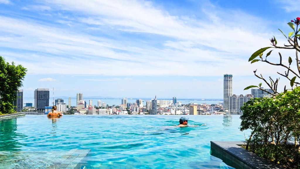 a group of people swimming in the infinity pool of a building at [InfinityPool][9px] Beacon Executive Suites in George Town