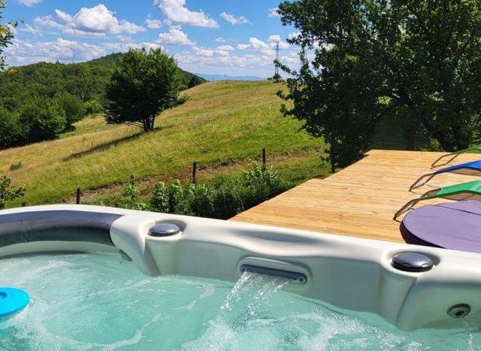 a hot tub in a field with a wooden deck at Chata Barbora in Uhliská