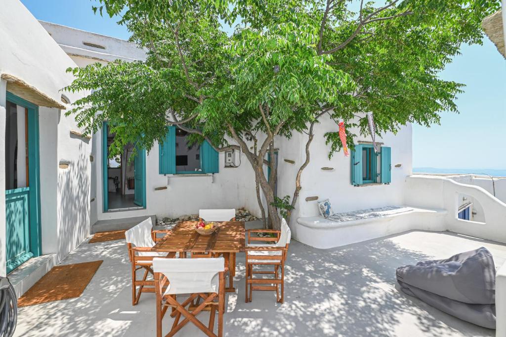 a patio with a table and chairs and a tree at Tinos Traditional Patio House in Arnados