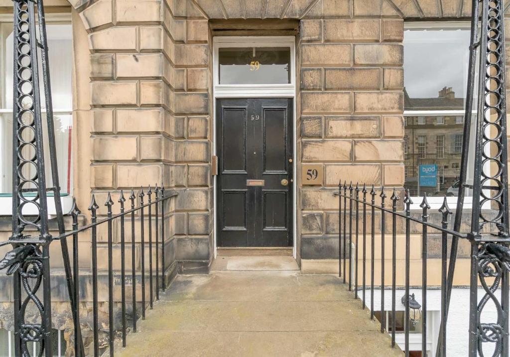 eine schwarze Tür an der Seite eines Gebäudes in der Unterkunft Melville Street Apartment in Edinburgh