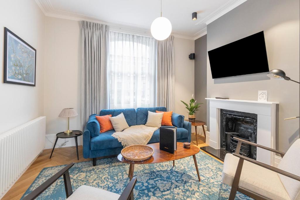 a living room with a blue couch and a fireplace at Spacious Private home with King sized bed and Garden newly renovated in London